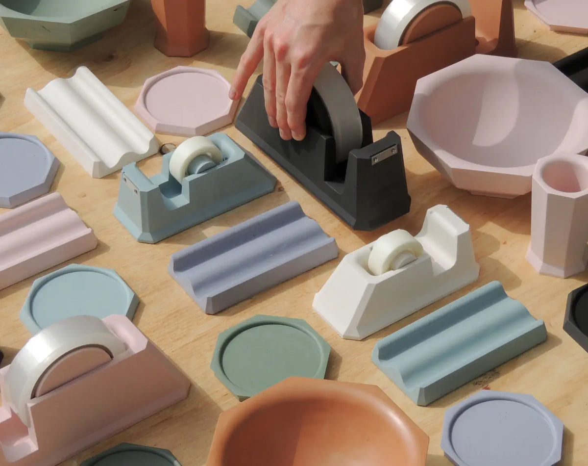 Assorted Jesmonite homeware in pastel tones — tape dispensers, bowls, coasters and cups. Image courtesy of jesmonite.com