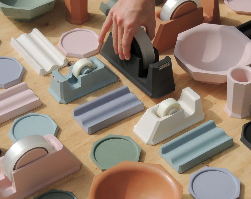Assorted Jesmonite homeware in pastel tones — tape dispensers, bowls, coasters and cups. Image courtesy of jesmonite.com