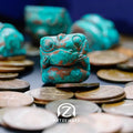 Chomper artisan keycap in Copper Patina finish surrounded by coins, close-up front view