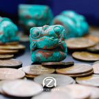 Chomper artisan keycap in Copper Patina finish surrounded by coins, close-up front view