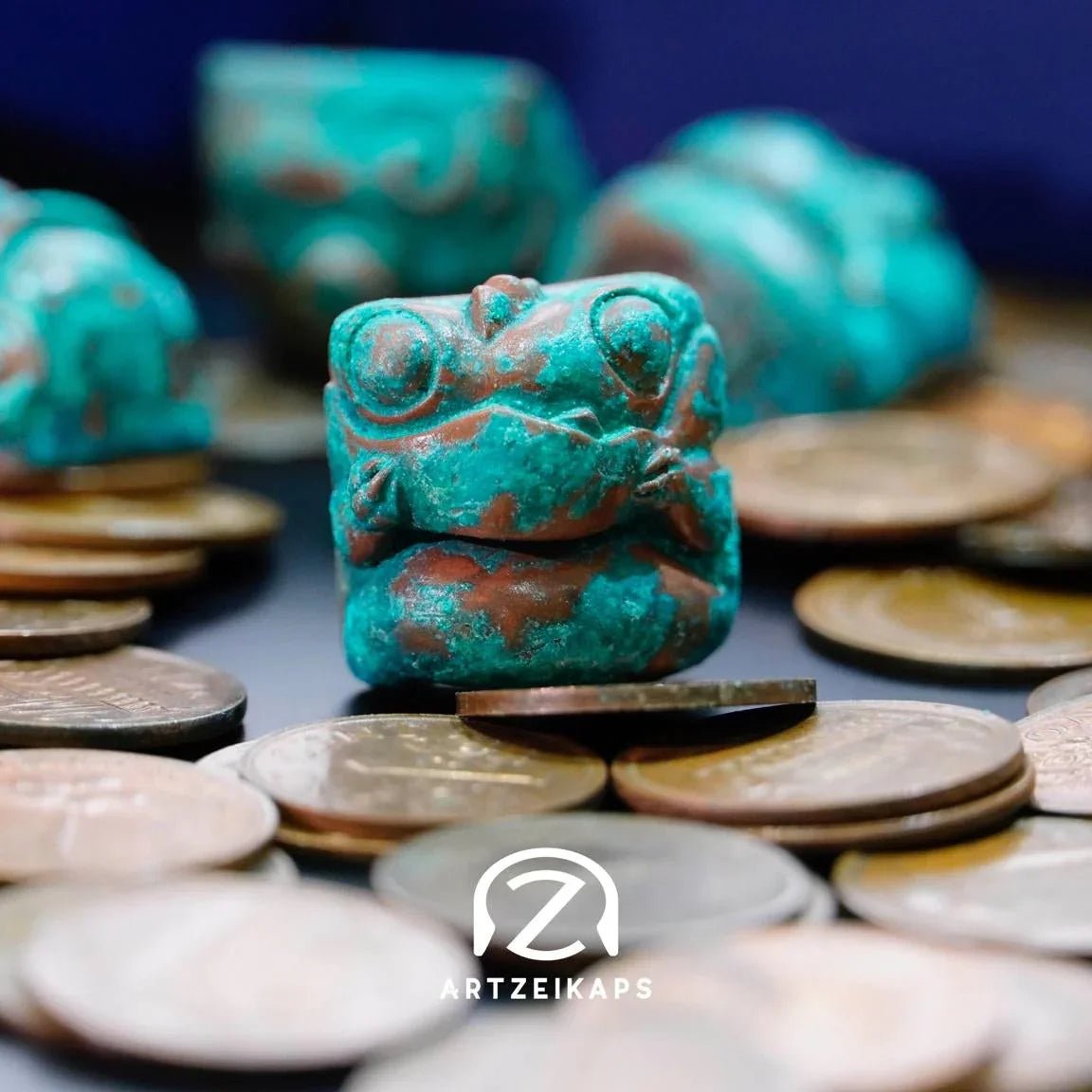 Chomper artisan keycap in Copper Patina finish surrounded by coins, close-up front view