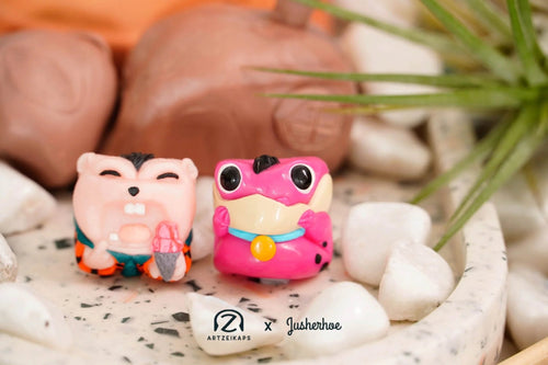 Chomper Flintstones artisan keycap front and back view with white pebbles and greenery — Artzeikaps x Jusherhoe collab