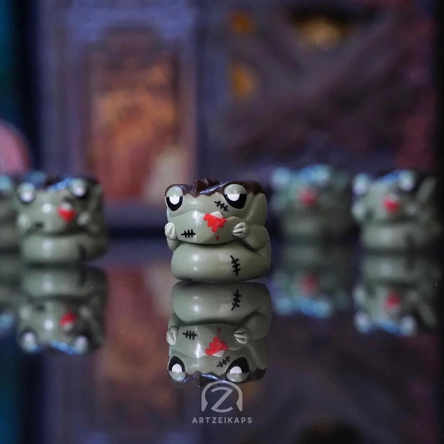 Chomper FrankenZ artisan keycap in zombie green with red stitching details, close-up front view with reflection