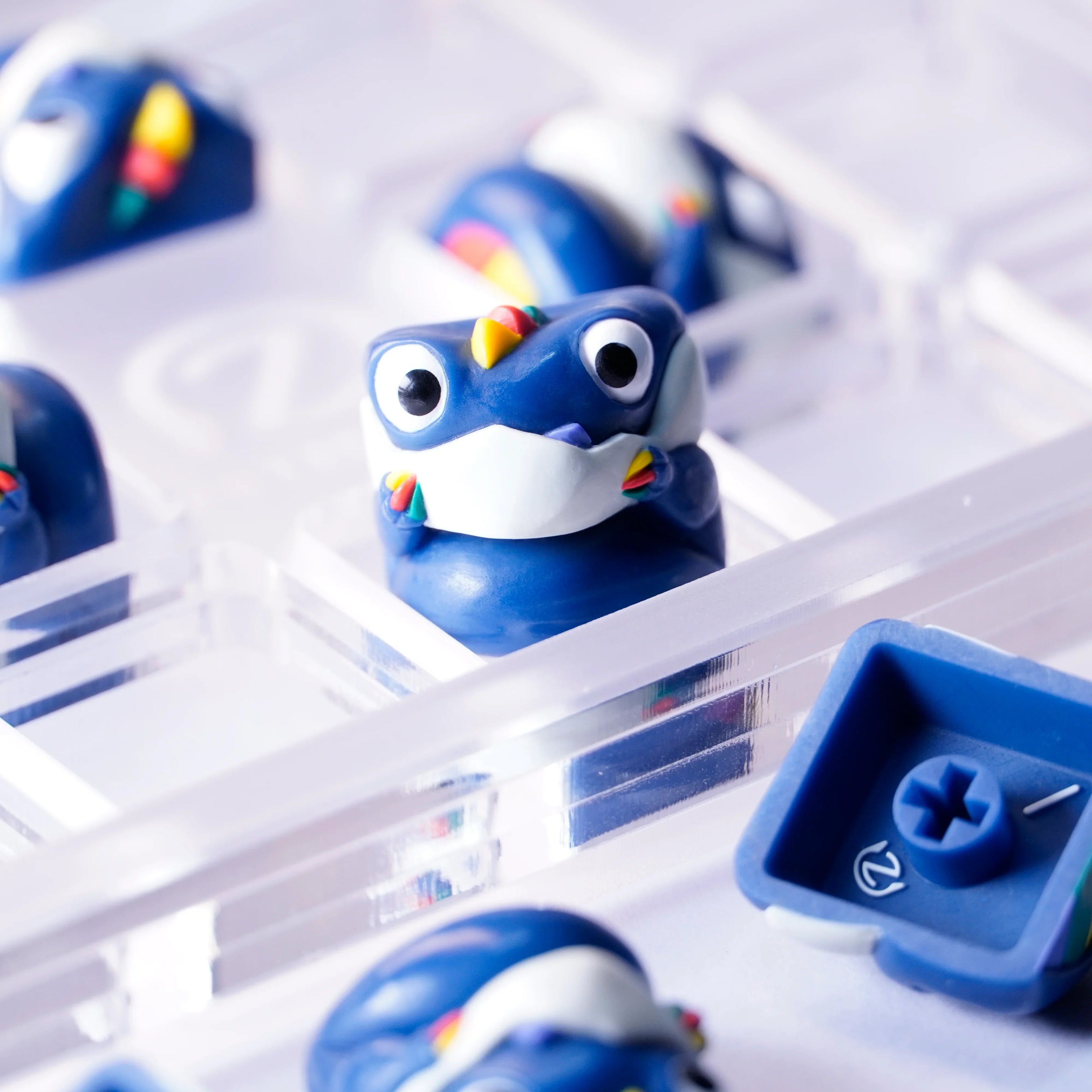 Chomper GMK³ artisan keycap in blue with rainbow details, front and back view in acrylic tray