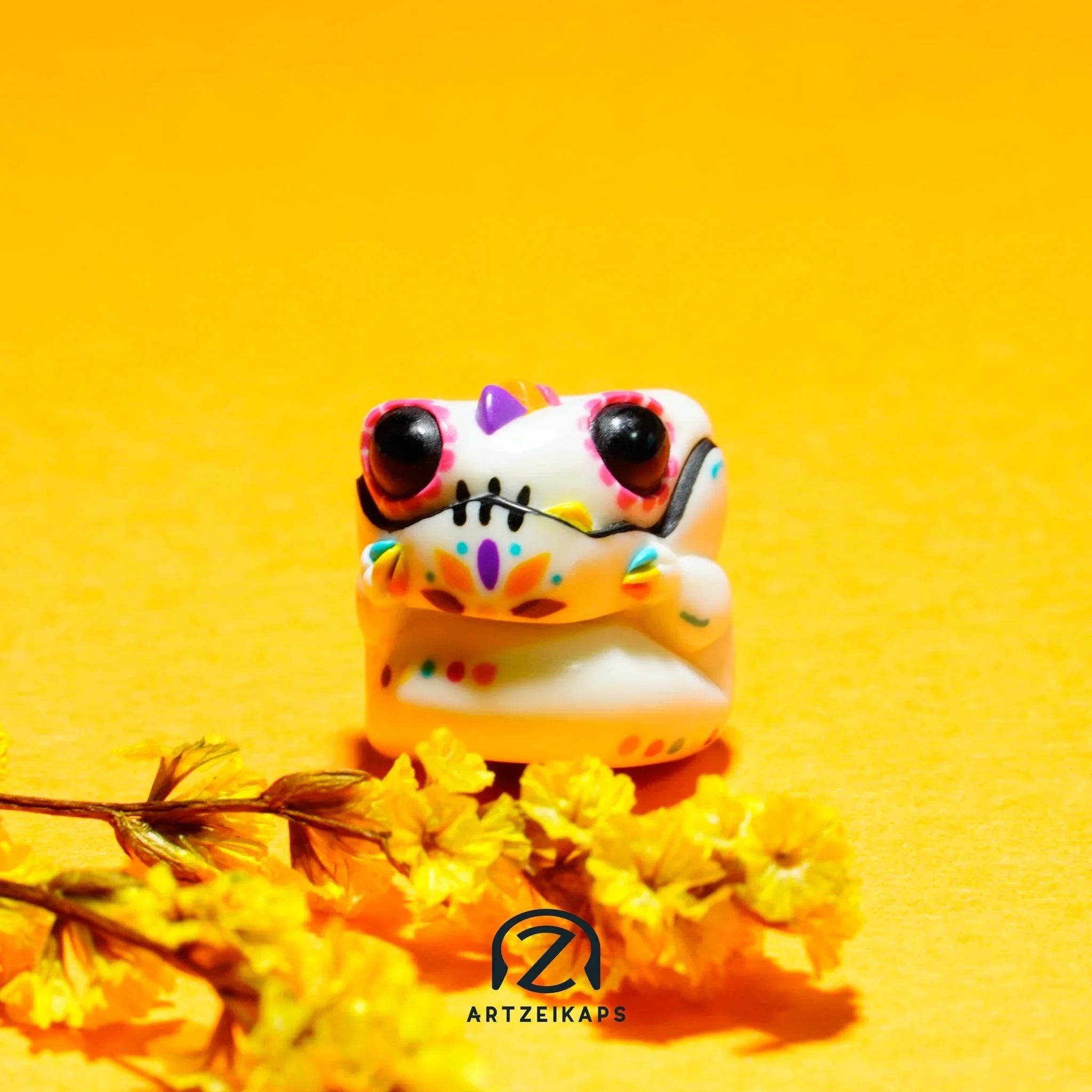 Chomper GMK Mictlan artisan keycap front view on vibrant yellow background with marigold flowers