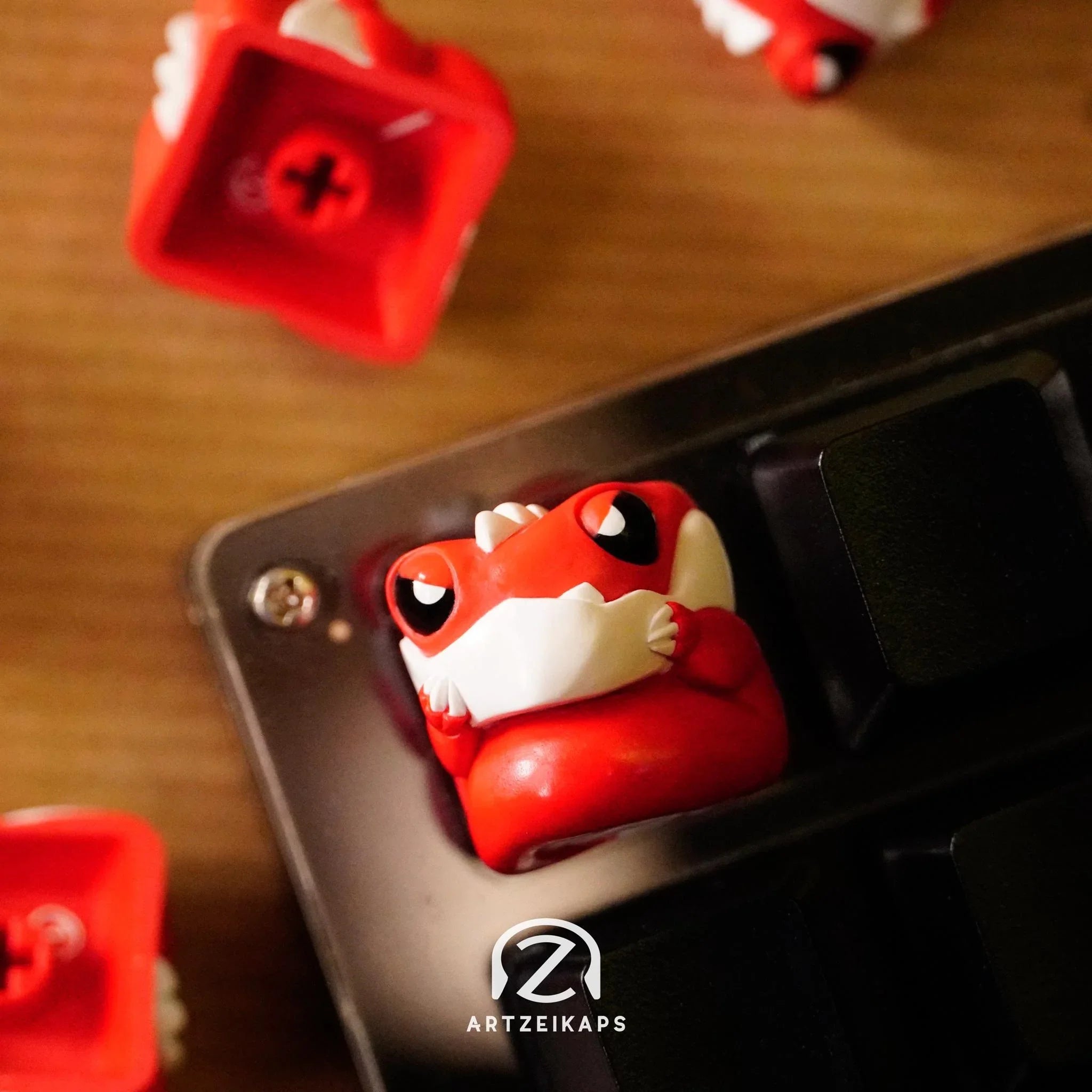 Chomper Lil' Red Grump artisan keycap in red with white teeth detail, mounted on black mechanical keyboard with red keycaps on wooden surface