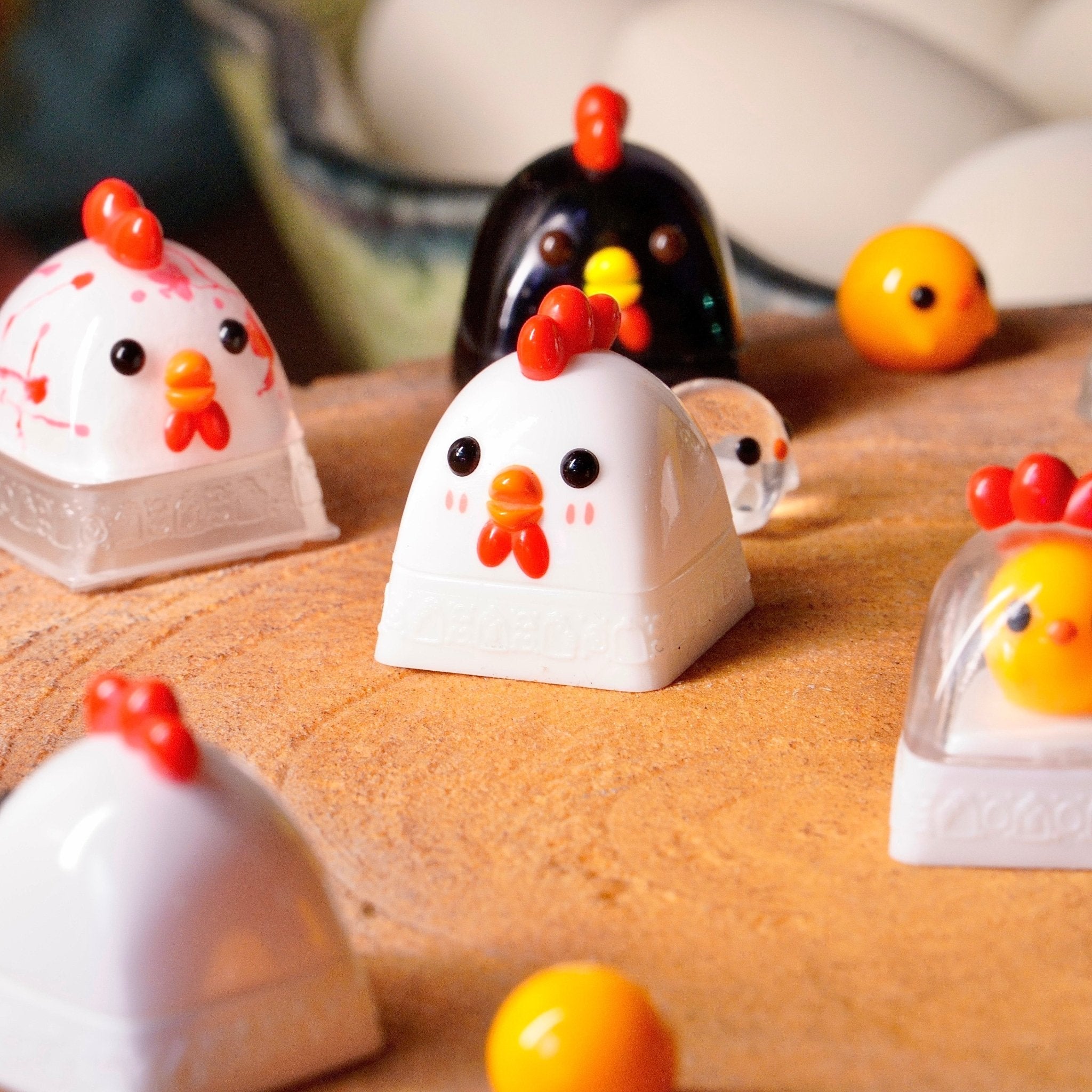 Handmade chicken and chick artisan keycaps in white, black and yellow on a wooden surface