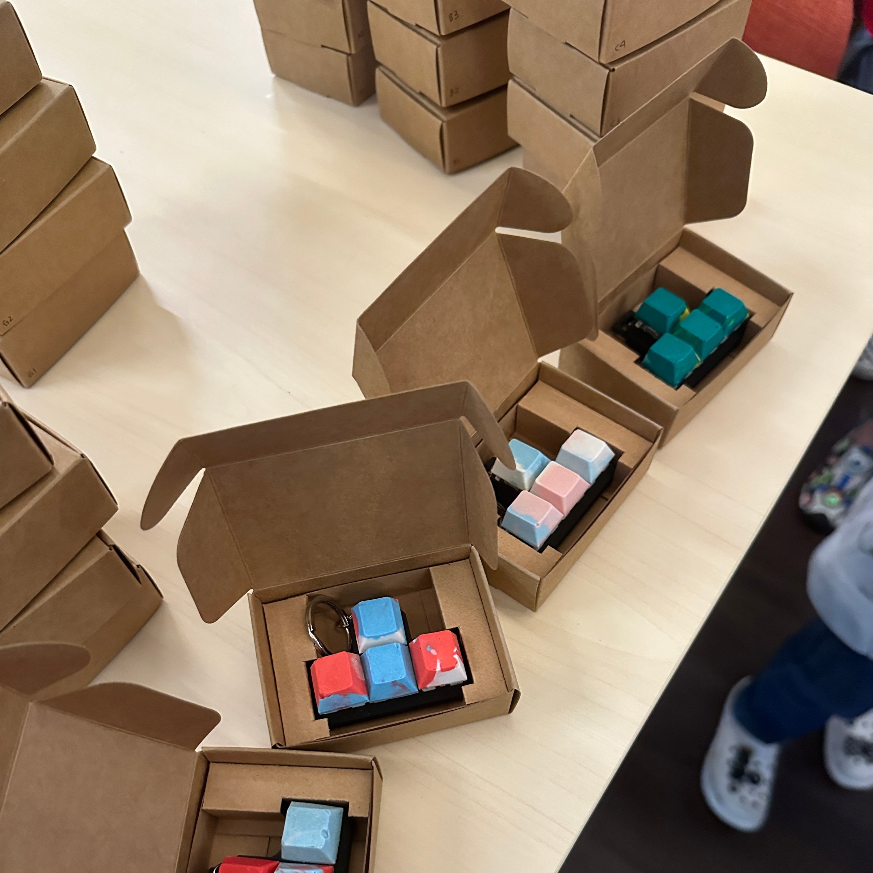 Handmade artisan keycaps in pastel colors packaged in cardboard boxes after a mechanical keyboard keycap workshop.