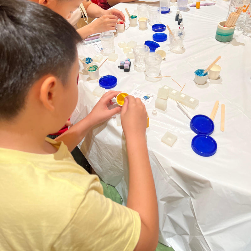 Children engaged in WASD keycap Workshop with various materials on a table.