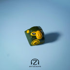 Smunkey Fall '21 artisan keycap in olive green, solo front view on light blue background