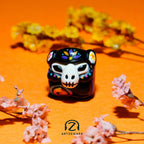 Smunkey GMK Mictlan artisan keycap dark colourway front view with marigold flowers on orange background