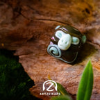 Smunkey GMK November Fog artisan keycap in dark brown, front view on mossy bark surface
