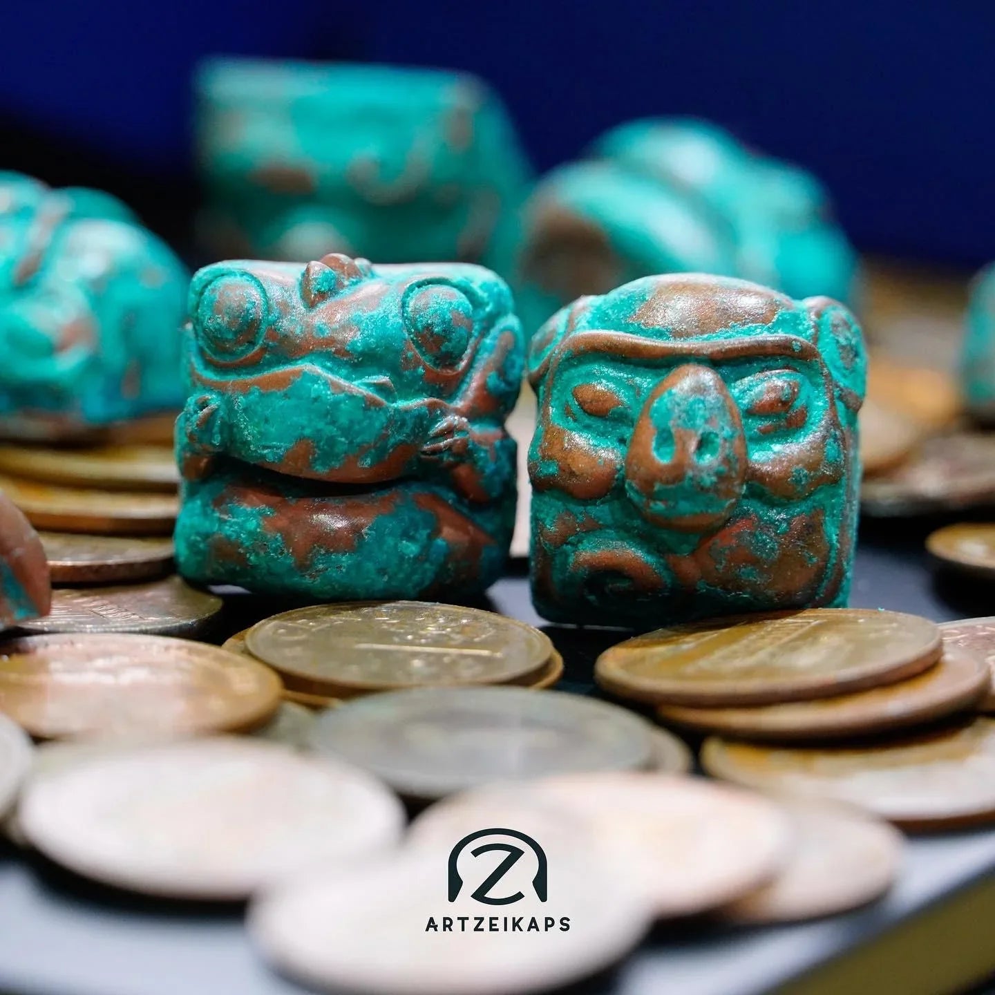 Smunkey and Chomper artisan keycap in Copper Patina finish on a pile of coins, side angle view