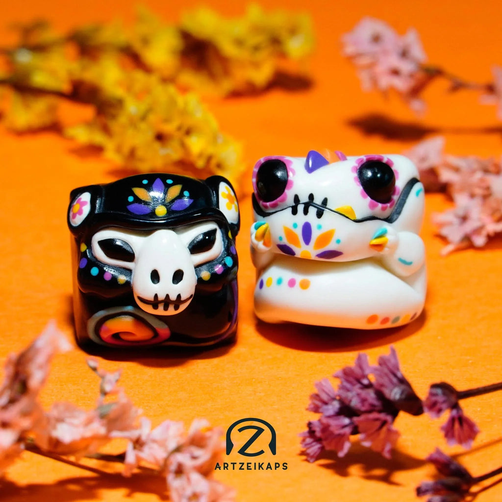 Smunkey and Chomper GMK Mictlan artisan keycap light and dark colourway pair amongst marigold flowers on orange background